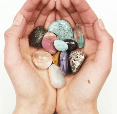 hand holding various colourful crystals