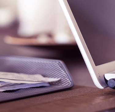 a laptop computer sitting on a desk with a stack of papers