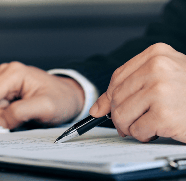 a person in a suit and tie is writing on a notebook