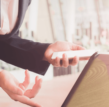 suit holding phone looking at computer