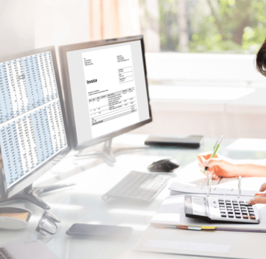 a woman sitting at a desk with a laptop and a laptop