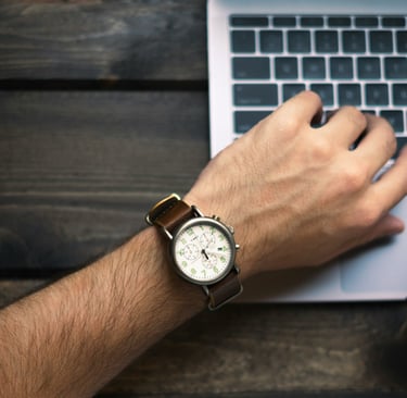 a man's wrist watch and a watch on a laptop