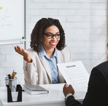 a recruiter in a business suit sitting at a desk interviewing a candidate