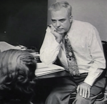Milton H Erickson sitting at a desk
