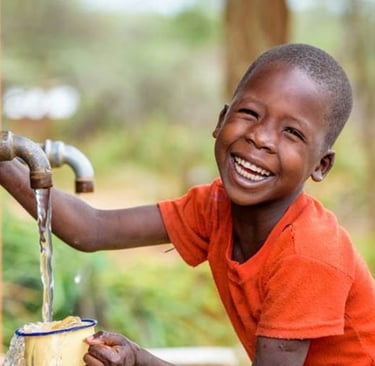 a young boy is smiling and holding a cup of water
