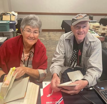 a woman and a man sit at a desk with reference books