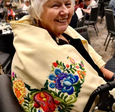 a smiling woman with an embrodiered shawl
