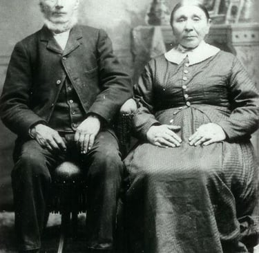 A man with a white beard sits next to a womanwith