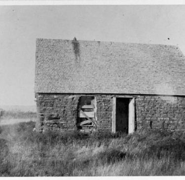a black and white image of a sod house on the prairie