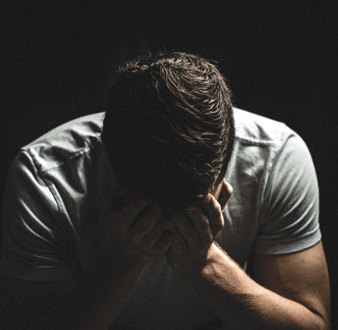a man in a white shirt is holding his hands to his face
