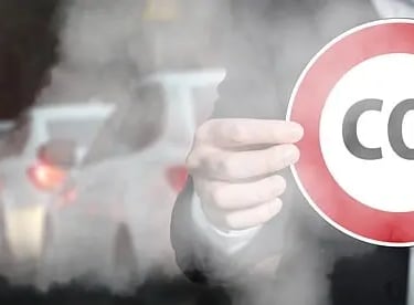 macchine in moto e un uomo con un cartello contro lo smog con la scritta co2