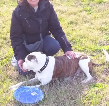 a woman in a black jacket and a dog in a field