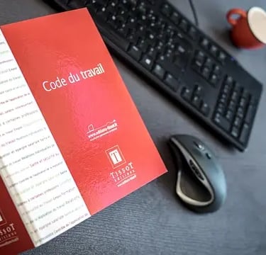 libro rosso con scritto code du travail e tastiera del pc