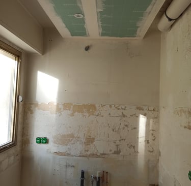 Rénovation de cuisine en cours avec tuyaux de plomberie apparents, plafond en placo et câblage 
