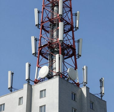 Technician adjusting radio equipment on a rooftop with city skyline in the background