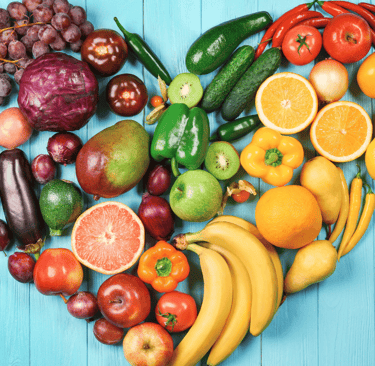 a heart shaped arrangement of fruits and vegetables organised by the colour of the rainbow