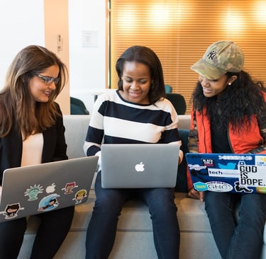 three women sitting on sofa with MacBook