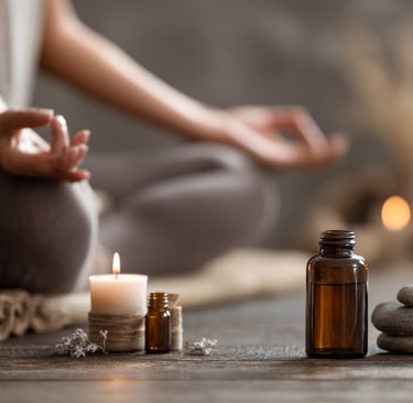 Meditative scene with candles, essential oils, and a person sitting in a grounding pose