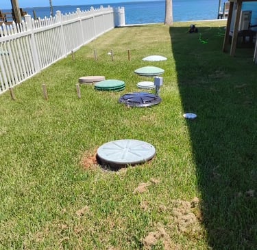 Septic system beside a stilt foundation home with coastal waters behind it