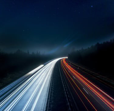 Fast-moving light trails on a highway at night, representing speed, innovation, and technological ad