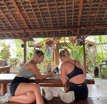 two women sitting on a bench in a wooden table