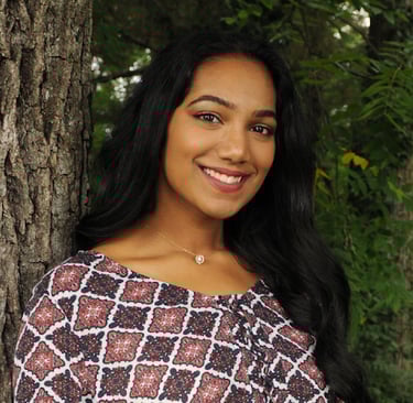 a headshot of a woman with long hair in front of a tree