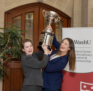 Two women in suits lift a trophy above their heads