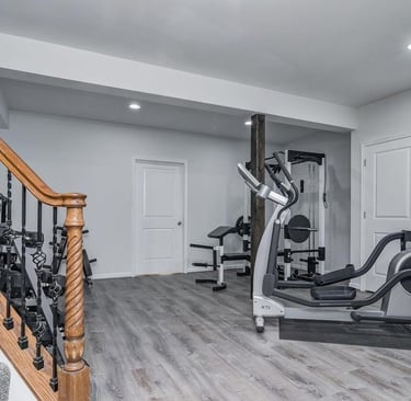 Exercise room with grey wood pattern LVT, several closets, and gym equipment