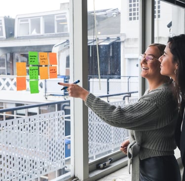 duas-mulheres-conversando-em-frente-à-uma-janela-com-post-its-colados