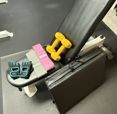 Home gym setup with a bench, dumbbells, resistance bands, a mat, and workout gloves.