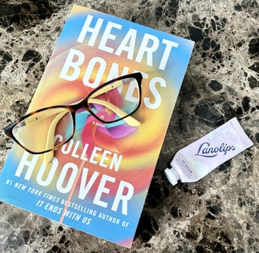 Lanolips lip balm on a nightstand beside a book and reading glasses ready for a nightly routine