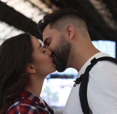 Una pareja dándose un beso al despedirse en una estación de tren porque viven lejos el uno del otro.