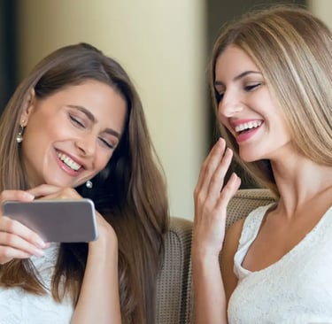 Dos amigas riendo mientras escuchan una canción personalizada de Musycol.