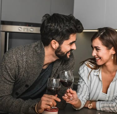 Pareja feliz celebrando su aniversario con una copa de vino escuchando una canción personalizada de Musycol.