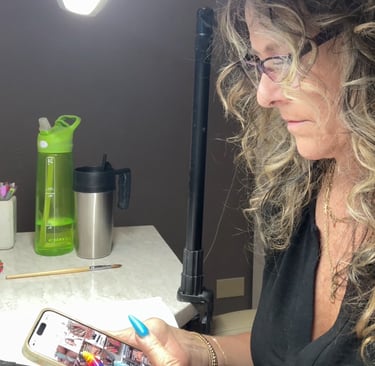 Nail technician looking at another nail tech’s social media feed, distracted from her own work