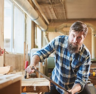 man with check shirt using a drawknife on timber