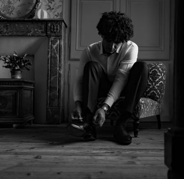 Un homme en chemise blanche assis laçant ses chaussures