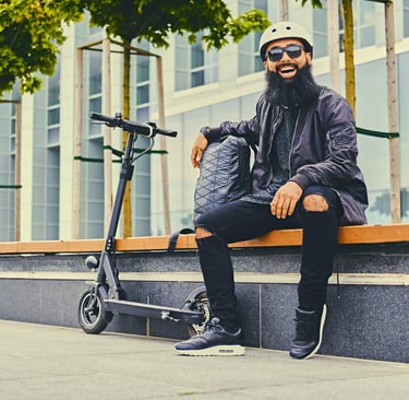 a man with a beard and a beard sitting on a bench with an electric scooter