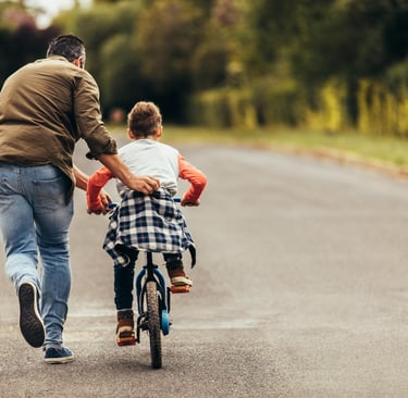 a man and a child riding bikes on a road