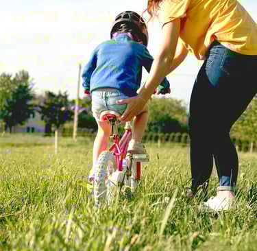 a woman in a yellow shirt and jeans and a helmet on a bicycle