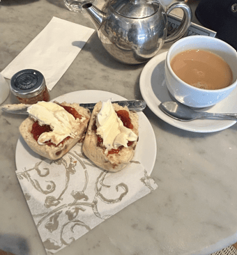 Una experiencia de té inglés con scones, nata espesa, mermelada y té caliente.