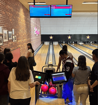 Un grupo de estudiantes jugando a los bolos en una bolera cubierta 