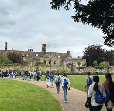 Estudiantes paseando por el jardín de un campus histórico con edificios de piedra