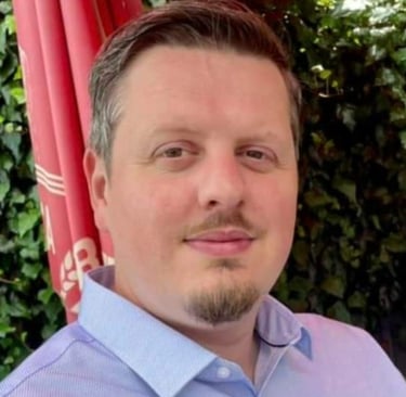 Dean Constantine, a white male, with brown eyes, hair and beard, in a blue collared shirt