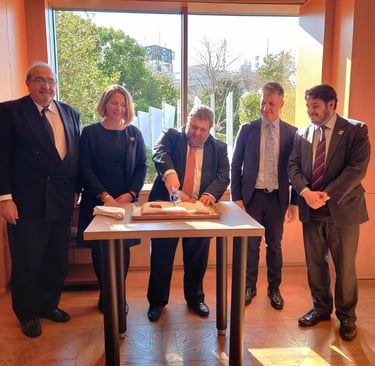a group of people standing around a table with a cake