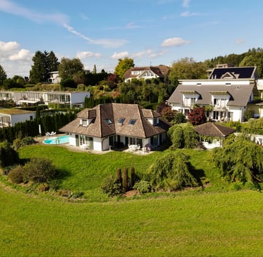 Drohnenaufnahme eines Einfamilienhauses mit Garten, Pool und umliegender Wohngegend