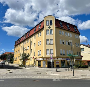 Gelbes Ärztehaus mit angeschlossener Apotheke – Außenansicht des Standorts der Hausarztpraxis