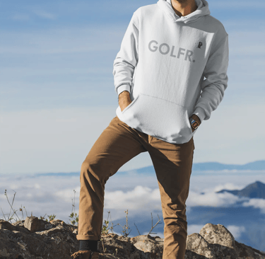 a man standing on a mountain top with a golf ball in his hand