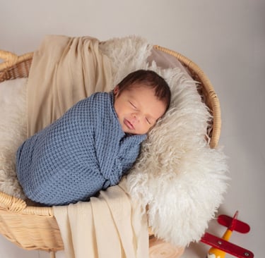 un bebé recién nacido dormido en un cesto de paja con un avión de juguete
