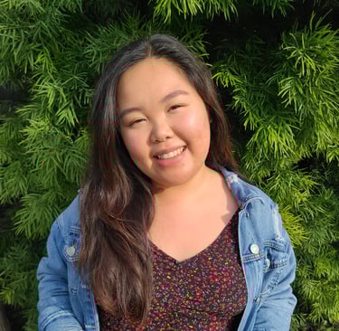 Elizabeth Nguyen, LMFT smiling with a green, luscious bush behind her